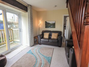 A living room with a sofa, a rug, a painting, and a wooden staircase.
