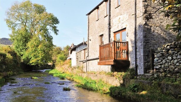 Un bâtiment en pierre doté d’un balcon en bois qui donne sur une rivière.