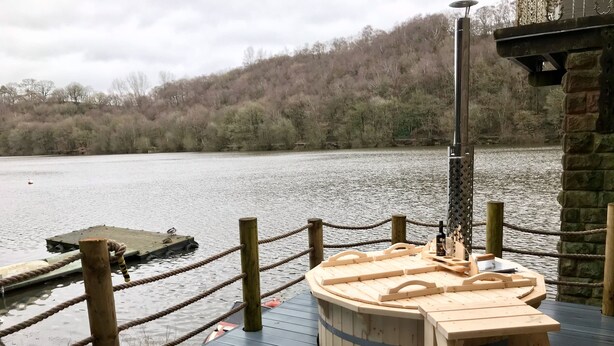 Eine Holzterrasse mit Tisch und Stühlen, einer Seilsicherung und einem Steg im Hintergrund.