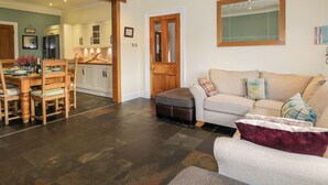 A spacious living room with a dining area, a kitchen, and a wooden door leading to another room.