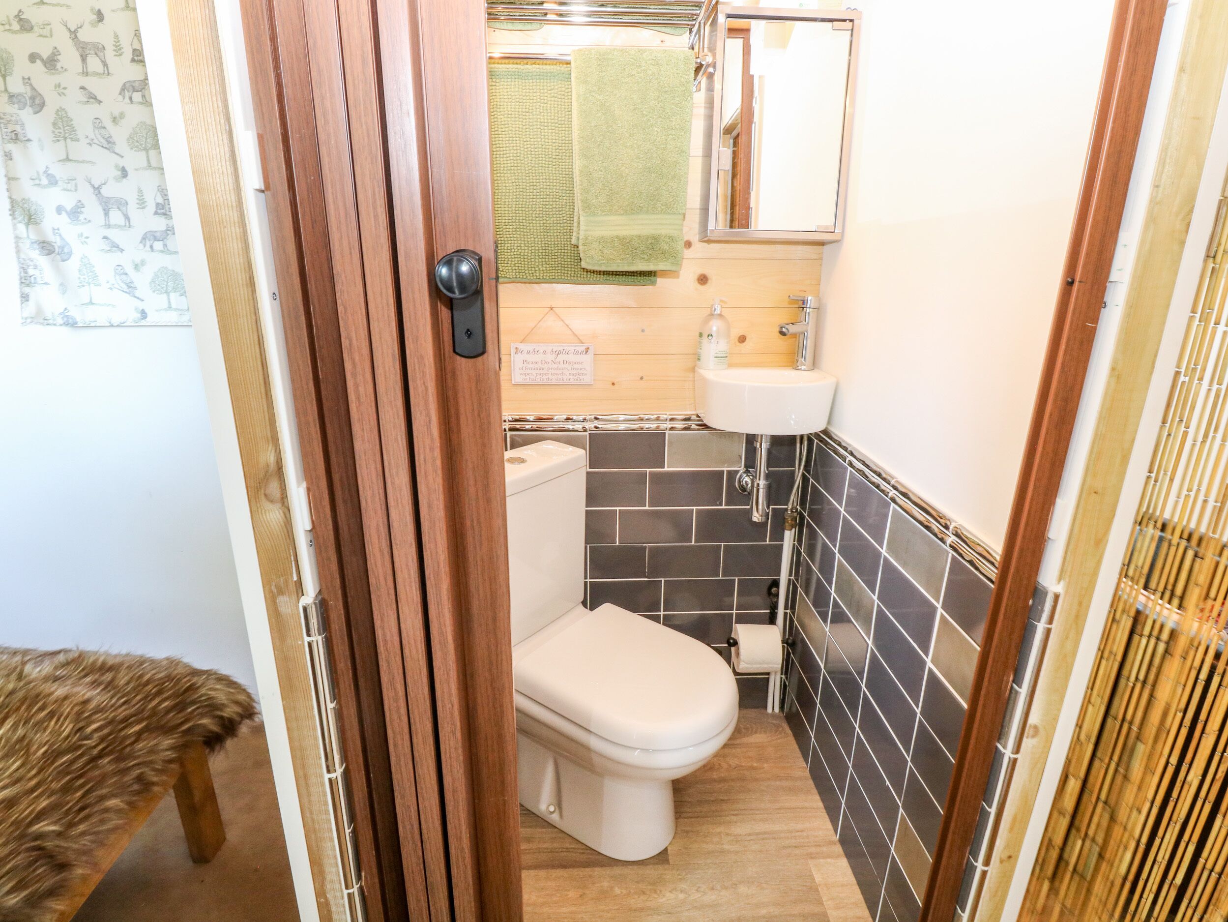 A compact bathroom with a toilet, sink, and a green towel hanging on the wall.