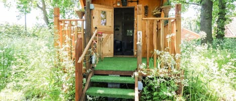 Een houten hutje met een groen dak, een deur en een klein veranda.
