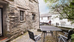 A stone building with a small balcony and a table with chairs outside. - Cherry Tree Cottage at Satterthwaite (Ulverston)