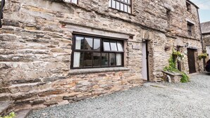 A stone building with a large window and a door, surrounded by gravel. - Cherry Tree Cottage at Satterthwaite (Ulverston)