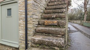 Un escalier en pierre mène à une porte en bois sur laquelle est apposée une enseigne indiquant « Magnolia Barn ».