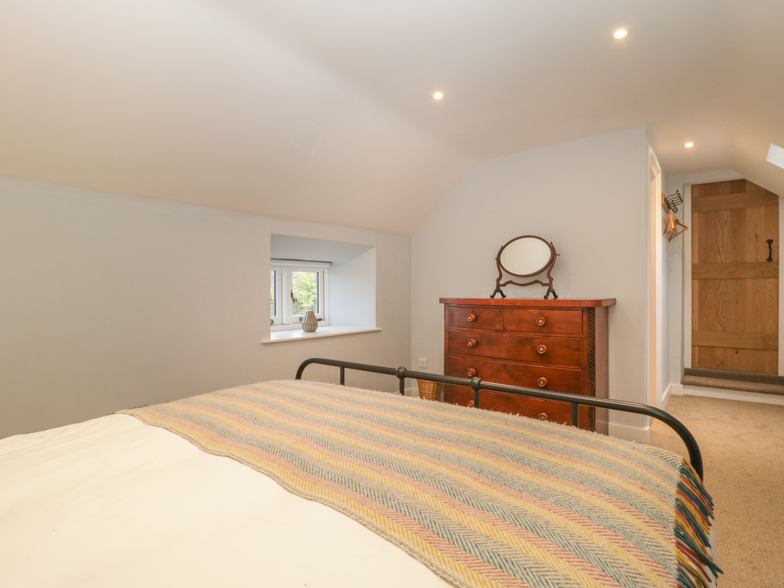 Un dormitorio con cama, cómoda, ventana y puerta.