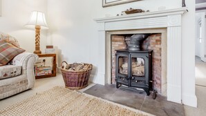 Una sala de estar con chimenea, un sofá, una lámpara y un cuadro en la pared.