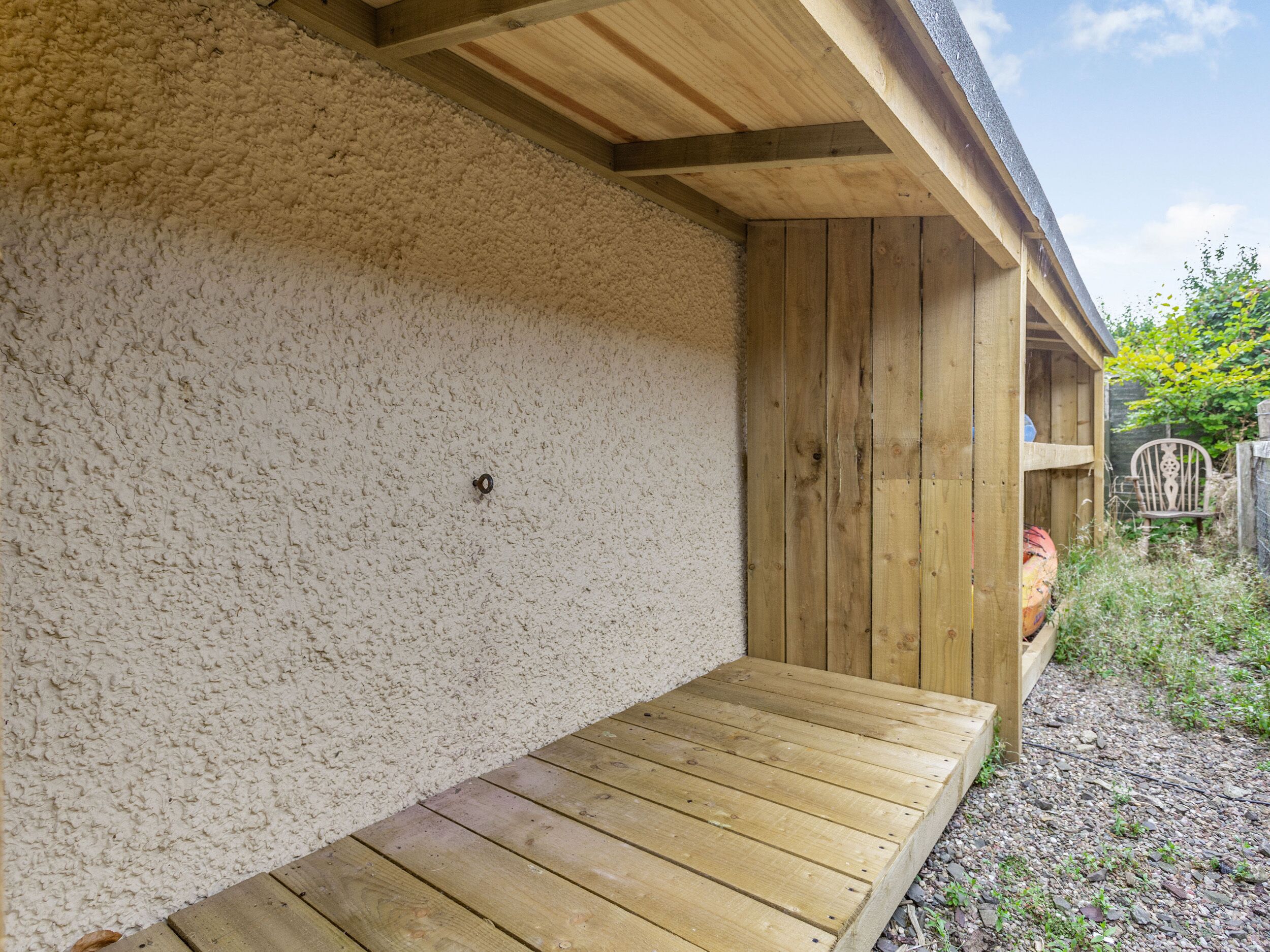 Una terraza de madera con un muro con textura y una puerta de madera.