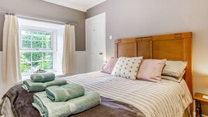 Un dormitorio con una cama grande, una ventana con cortinas y un cabecero de madera.