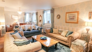 Ein gemütliches Wohnzimmer mit einem blauen Sofa, beigen Sesseln und einem Holztisch.