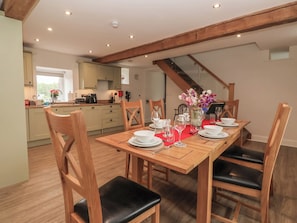 A dining area with a wooden table set for four, surrounded by wooden chairs with black cushions. - Miller's Wheel (Harrogate)