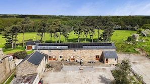 A stone building with a flat roof, solar panels, and a paved courtyard. - Miller's Wheel (Harrogate)