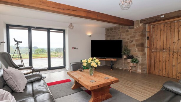 A modern living room with a sofa, a wooden coffee table, a television, and a telescope. - Ploughman's Rigg (Harrogate)