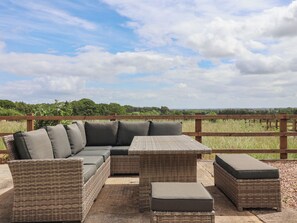 Un espace extérieur aménagé avec des meubles en osier et offrant une vue sur la campagne.