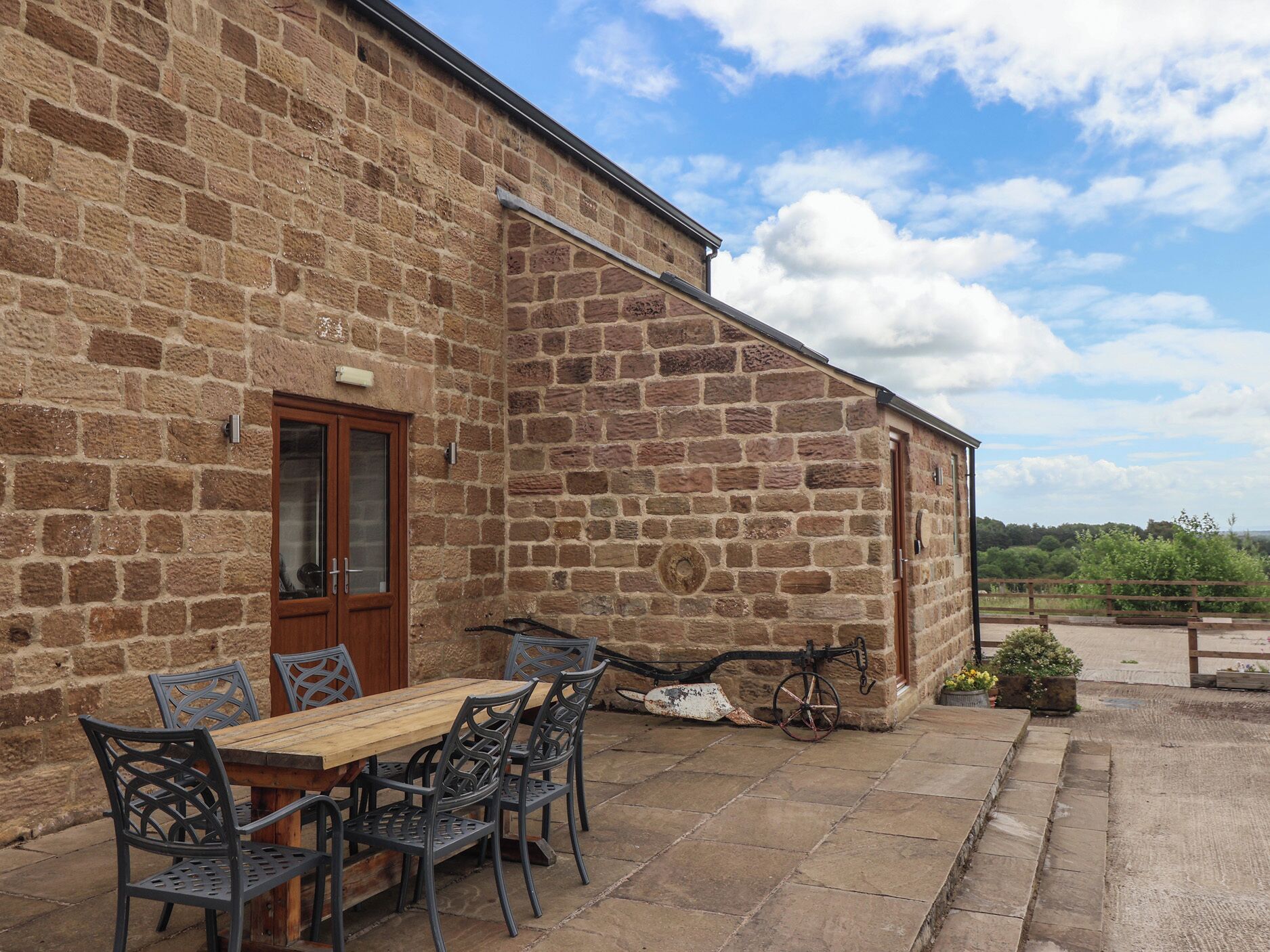 A stone building with a wooden door, a table with chairs, and a bicycle.