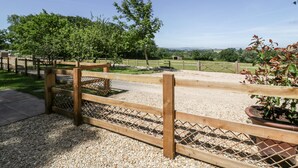 A gravel pathway leading to a wooden fence with a lattice design, surrounded by trees and a clear sky. - The Outlook (Taunton)