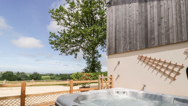 A hot tub with a wooden fence and a tree in the background. - The Outlook (Taunton)
