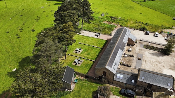 En vy över en fastighet, tagen från luften, som visar ett stort ladugårdsbyggnad, en inhägnad gård och ett litet hus.