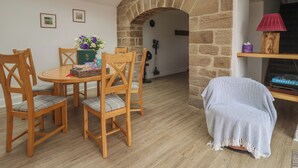 Una habitación acogedora con chimenea de piedra, una mesa de comedor con sillas y un tragaluz.