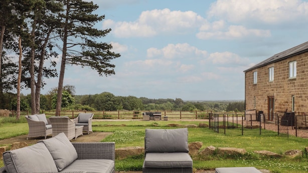 An outdoor seating area with wicker furniture and a stone building in the background. - Shepherd's Crook (Harrogate)