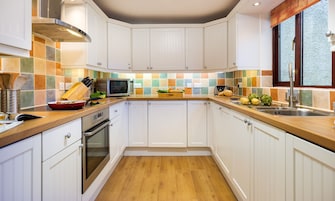 Uma cozinha moderna com armários brancos, bancada de madeira e painel de azulejos.