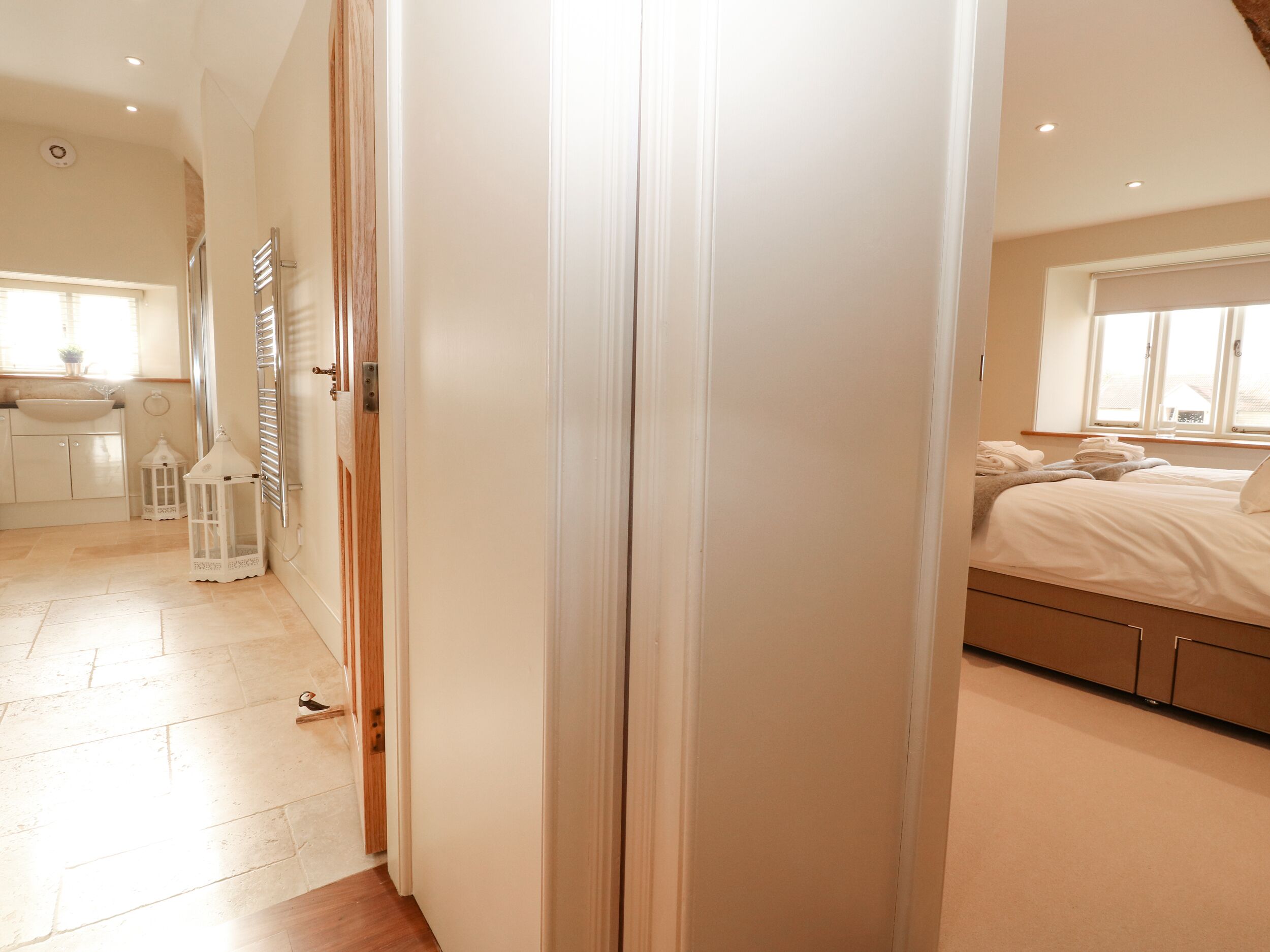 A bedroom with a bed, a window, and a bathroom with a sink and toilet.