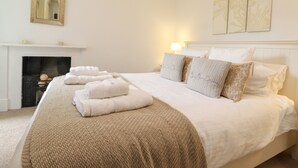 Un dormitorio ordenado con cama, almohadas y una manta.