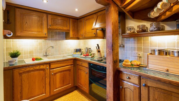 A kitchen with wooden cabinets, a sink, a stove, and a countertop with various kitchen items.