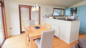 Une cuisine moderne dotée d’un îlot central, d’une table à manger en bois et de chaises recouvertes d’un tissu gris.