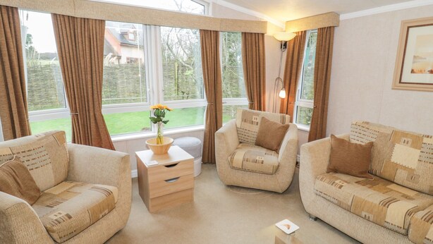 A cozy living room with two sofas, a wooden side table, and a floor lamp. - Banadlen Lodge (Brynteg)