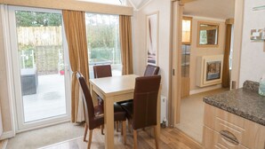 A modern kitchen with a granite countertop, wooden cabinets, and a built-in oven. - Banadlen Lodge (Brynteg)