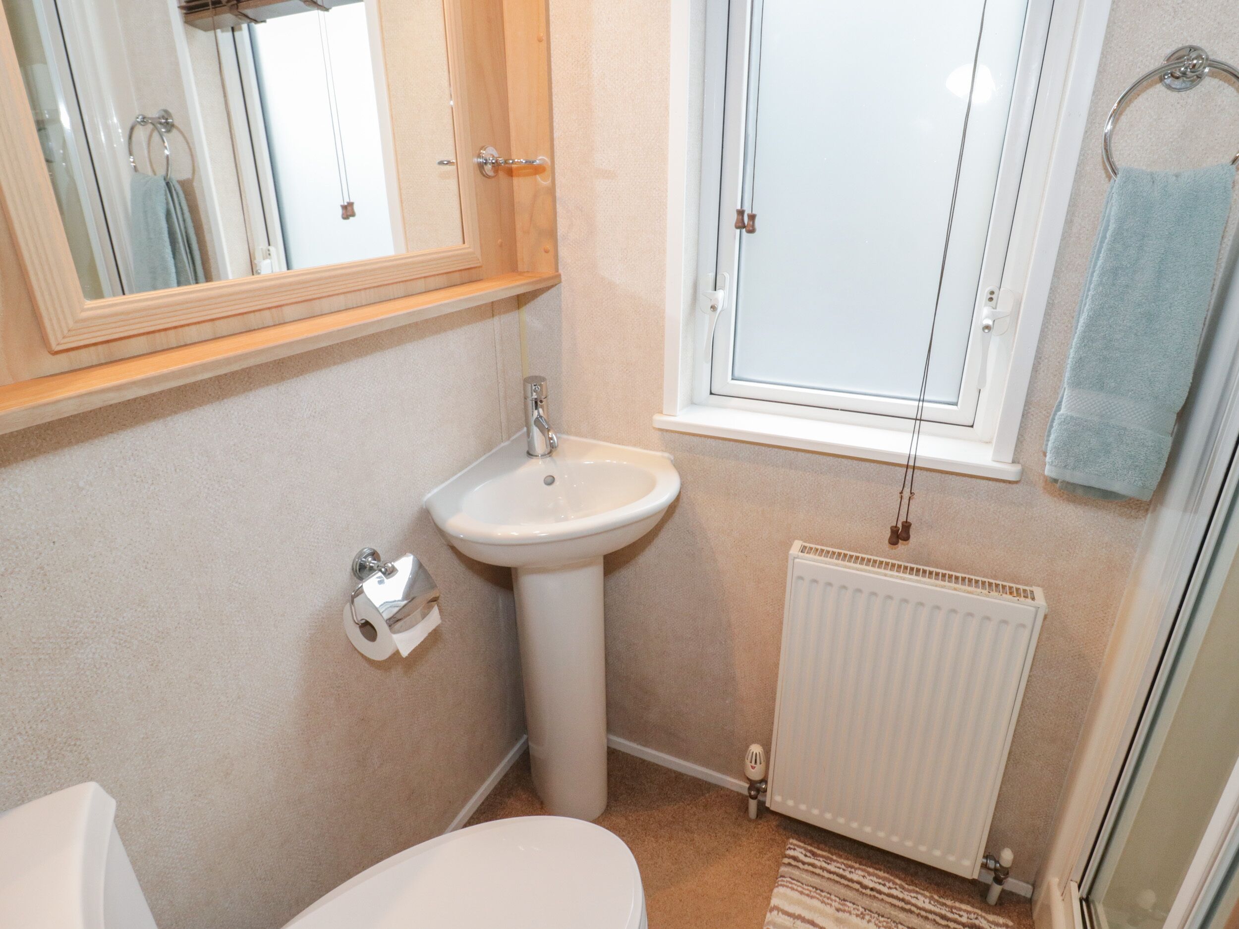 A compact bathroom with a white sink, toilet, and a mirror above the sink.
