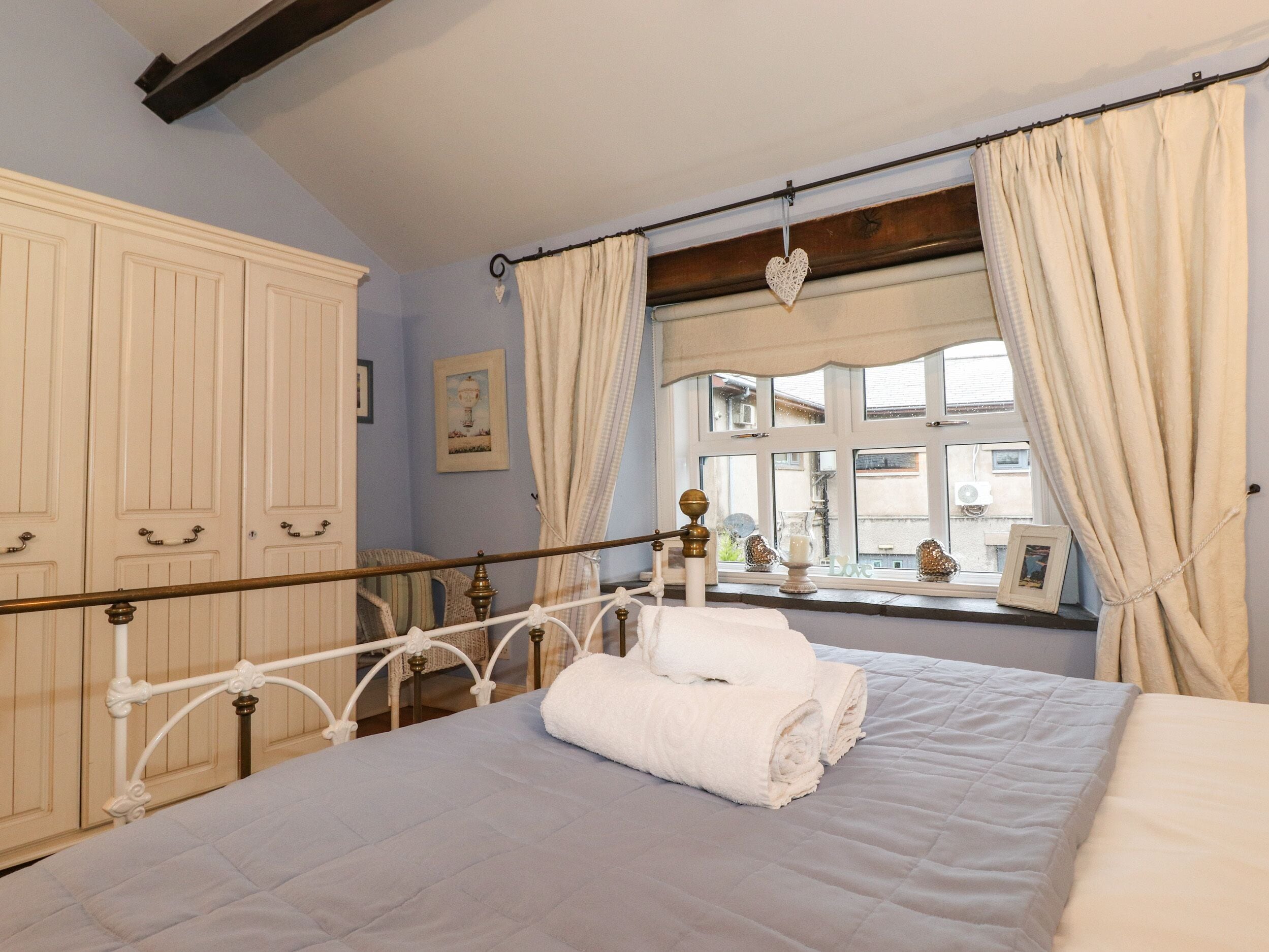 A bedroom with a bed, a window with curtains, and a wardrobe.