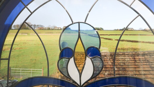 A stained glass window with a rural landscape view. - The Coach House (Bradford)