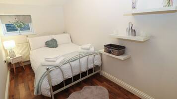 A neatly arranged bedroom with a bed, bedside table, lamp, and a small rug.
