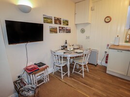 Una cocina pequeña y acogedora con una mesa de comedor, sillas y un televisor montado en la pared.