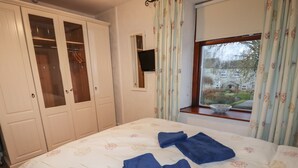 A bedroom with a bed, a window with a view, and a wardrobe. - Winskill Cottage (Settle)