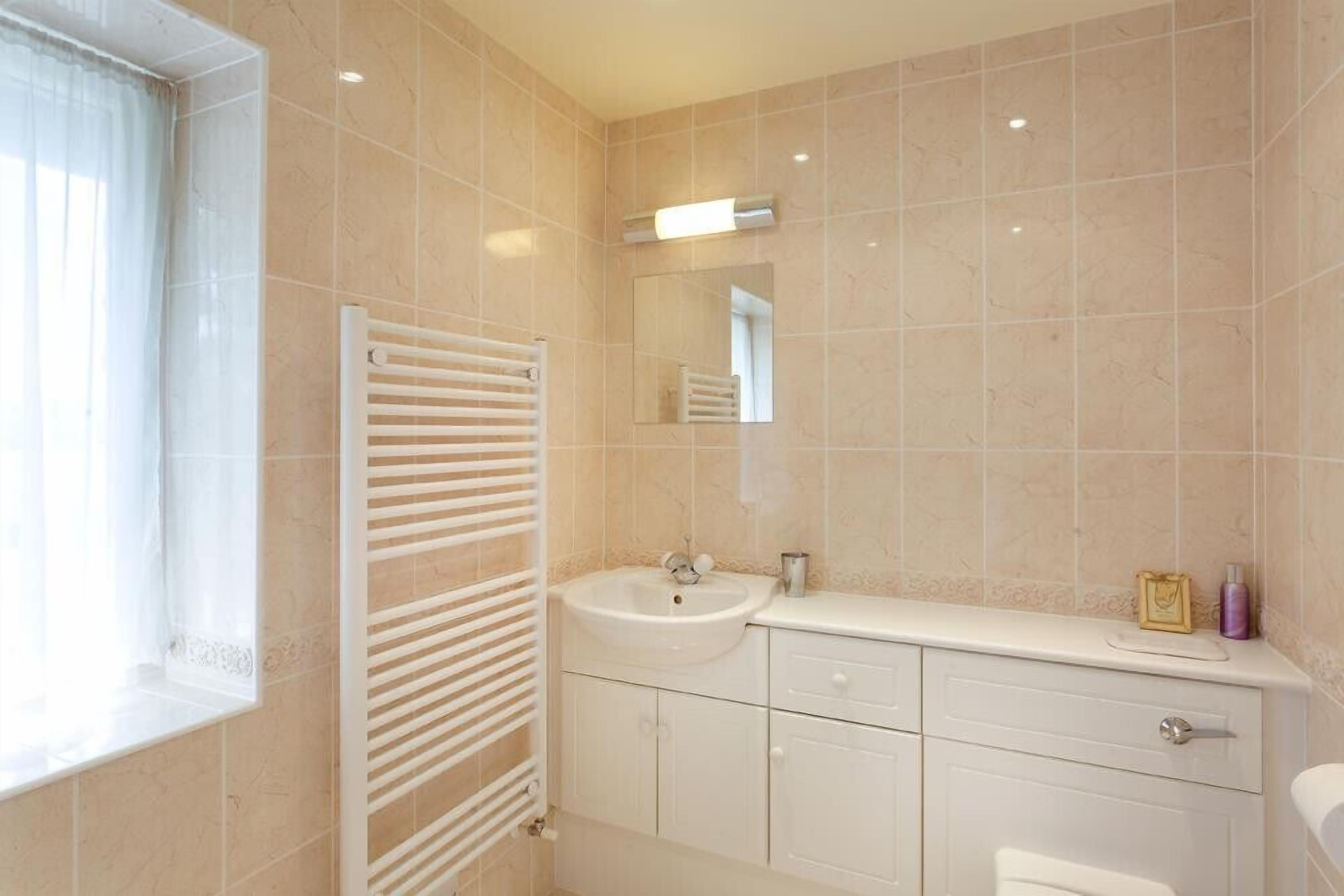 A bathroom with a sink, mirror, and towel rack.