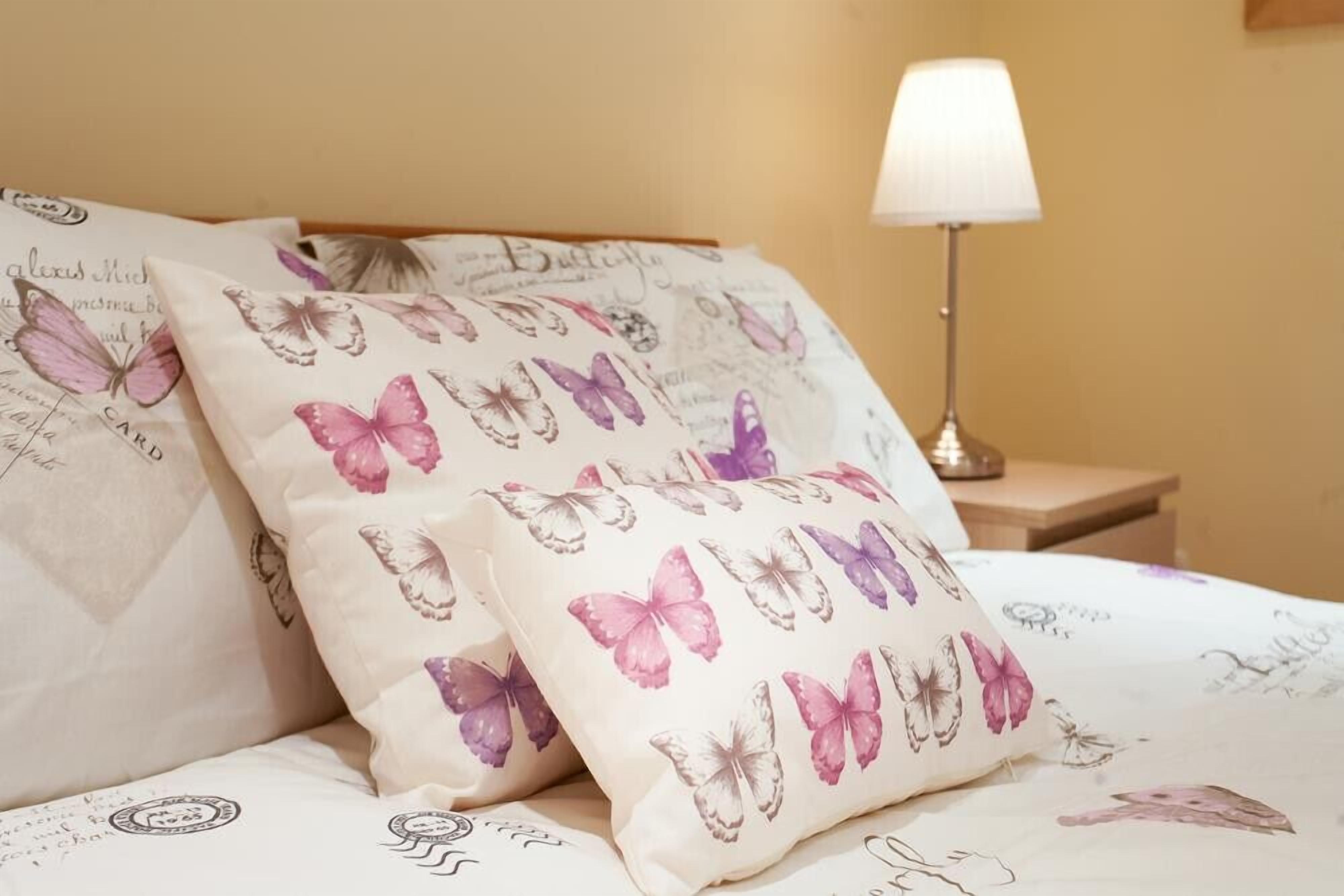 A bed with decorative pillows featuring butterfly patterns.
