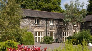 A stone building with multiple windows and a well-maintained garden in front. - The Old Barn (Windermere)