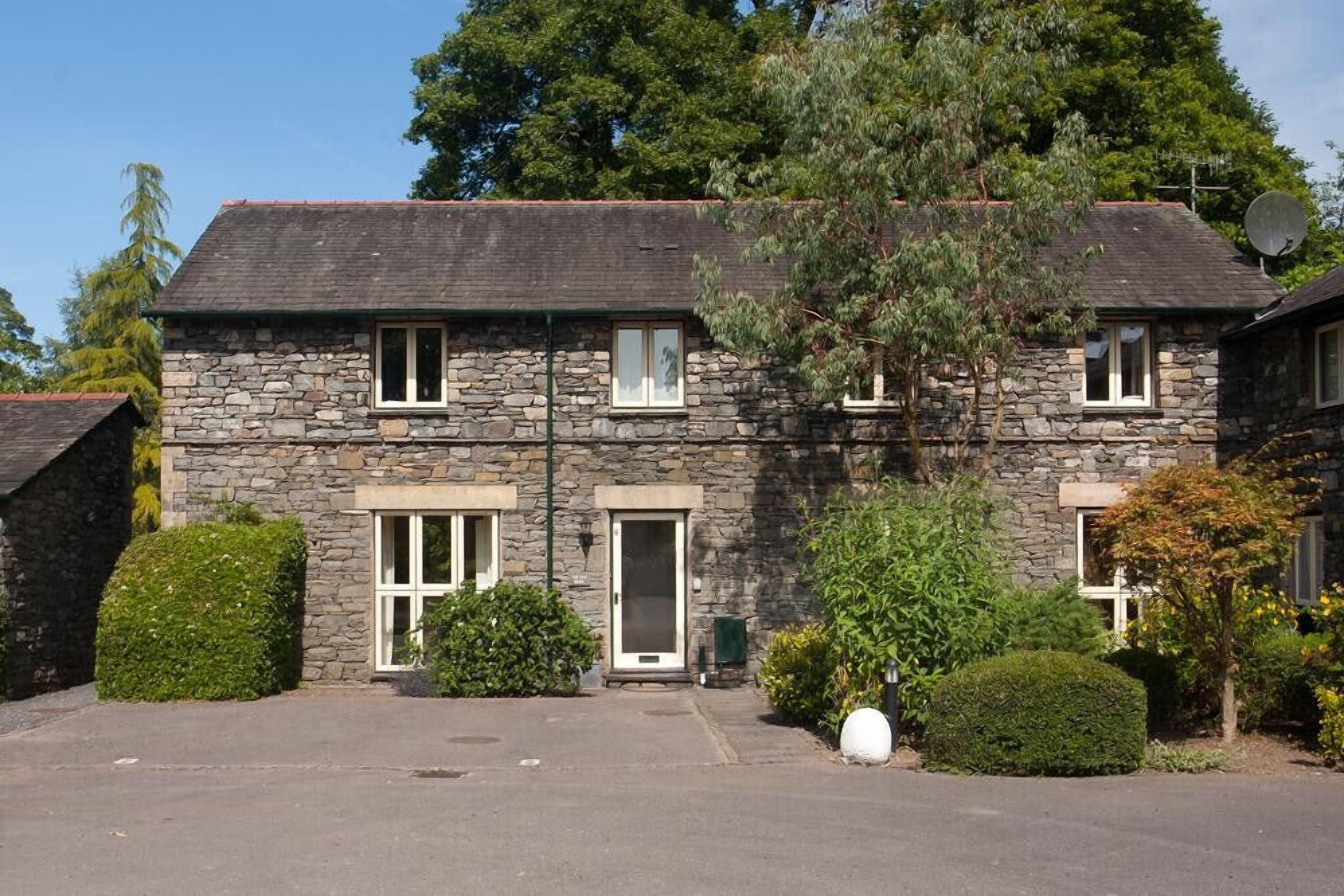 A stone house with a central entrance, multiple windows, and a satellite dish.