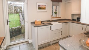 A modern kitchen with white cabinets, a granite countertop, and a built-in oven. - 1 Town Head (Buxton)