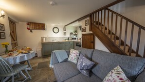 A cozy living room with a grey sofa, a dining table with chairs, and a kitchen in the background. - Crooks (Axbridge)