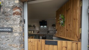 Une cuisine avec des meubles de rangement en bois, un mur en briques et une enseigne sur laquelle on peut lire « HÉSITANT ».