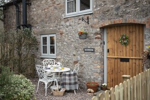 A stone building with a wooden door, a sign reading "Waverly," and a small garden area with a table and chairs. - Wavering (Axbridge)