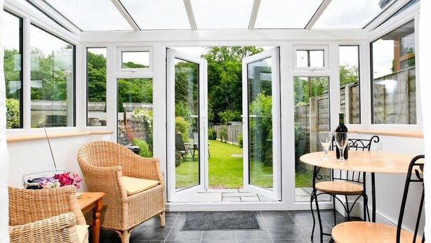 A conservatory with wicker furniture and a view of a garden. - Stone Cottage at Staveley (Kendal)