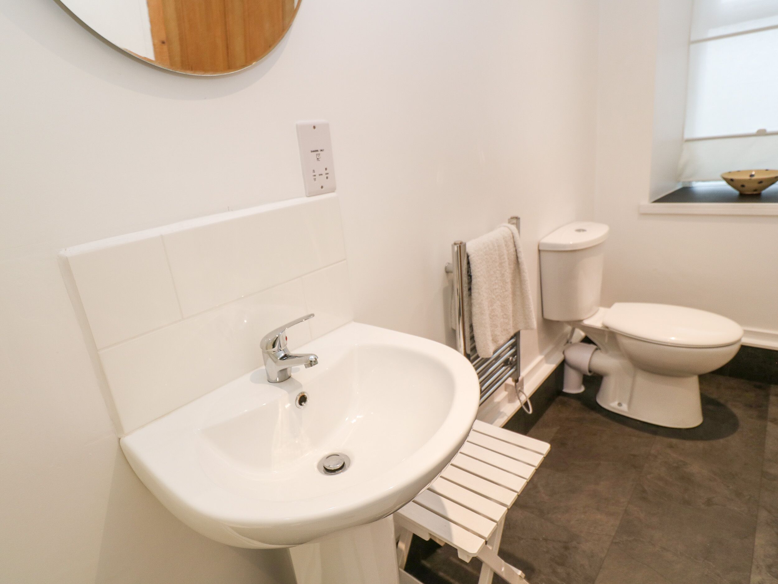 A bathroom with a white sink, toilet, and a small window.