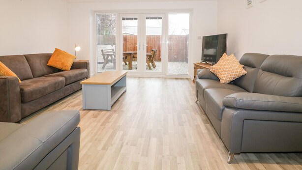 A modern living room with two sofas, a coffee table, and a TV. - Lily Cottage (Camelford)