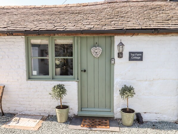 A cottage with a green door, a window, and a sign reading "Top Farm Cottage". - Top Farm Cottage (Oswestry)