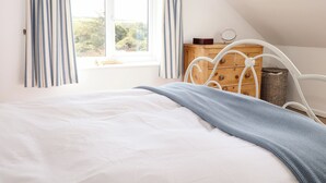 Un dormitorio con una cama, un aparador de madera y una ventana con cortinas.